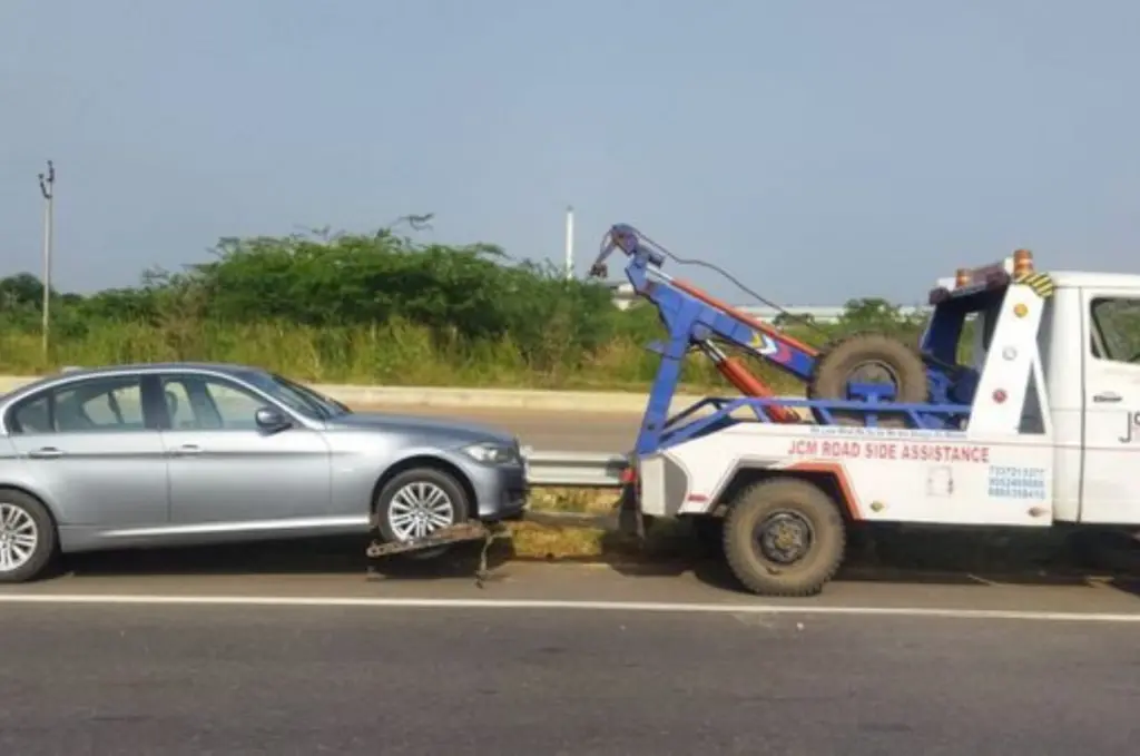 Person selling a car without a title to a cash car buyer with a damaged vehicle in the background.